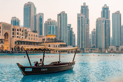 picture of a wooden boat in a lake in dubai and buildings in the background