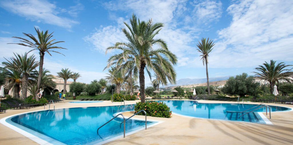 Outdoor pool with palm trees at AR Golf Almerimar Hotel