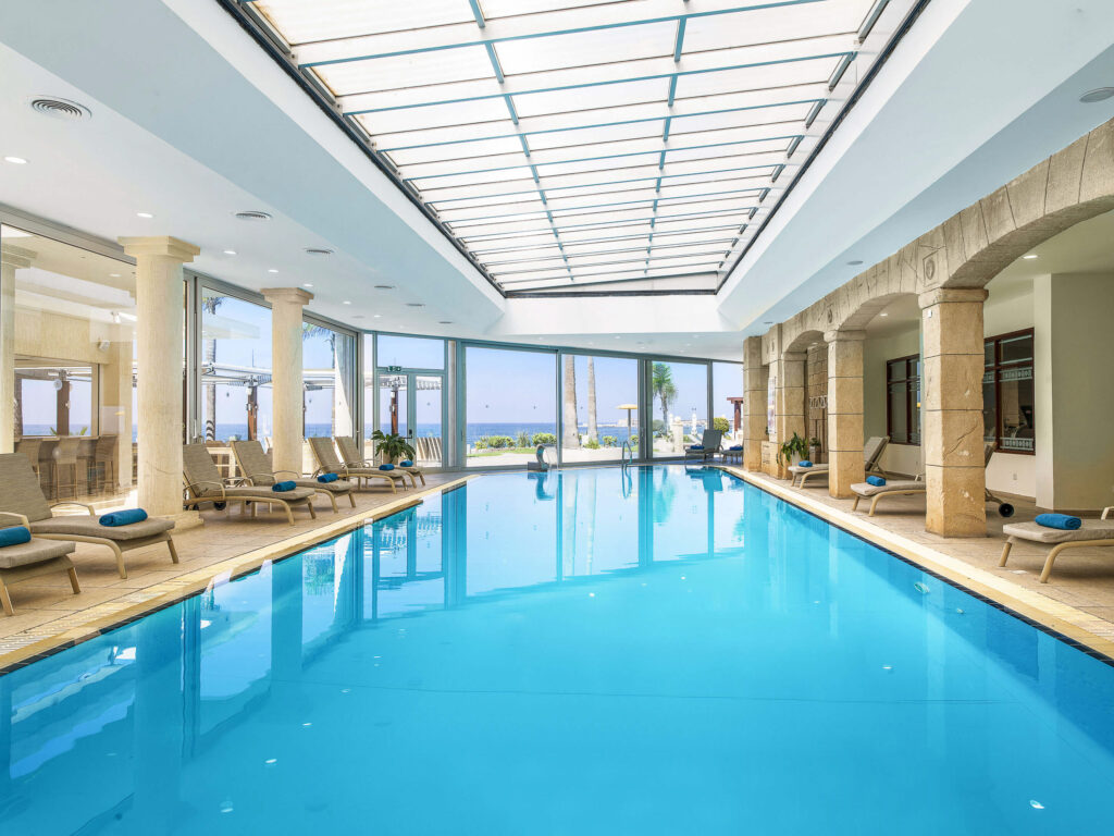 Indoor pool at Alexander The Great Beach Hotel with loungers