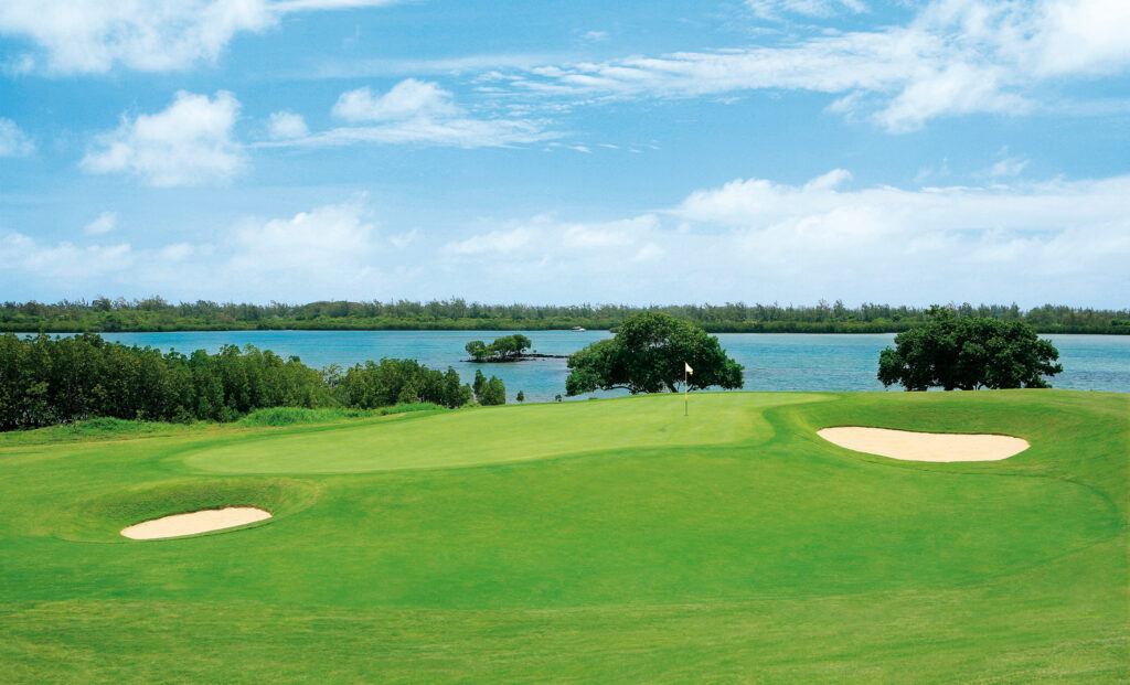 Hole with white flag at Anahita Golf Course with bunkers with ocean in background