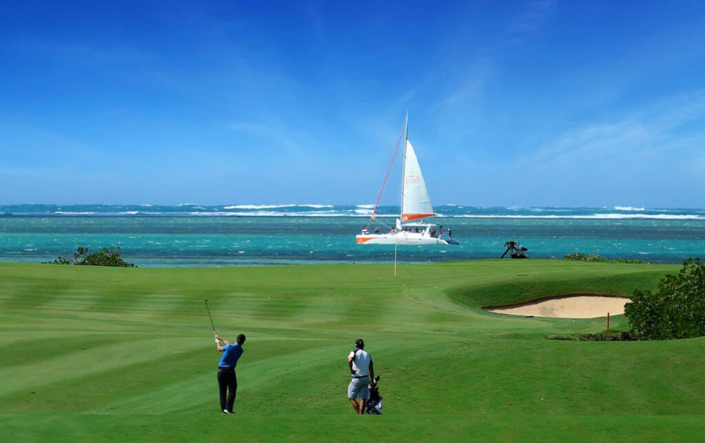 People playing golf at Anahita Golf Course with ocean and boat in background