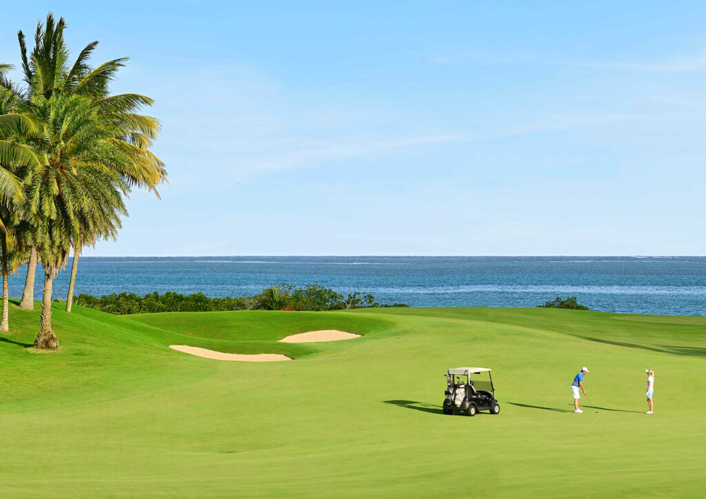 People playing golf on the fairway at Anahita Golf Course with bunkers and ocean in background