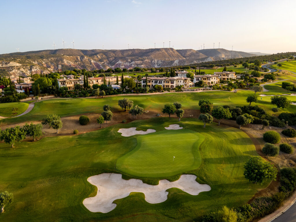 Hole with bunkers around at Aphrodite Hills PGA National Cyprus with villas and hills in background