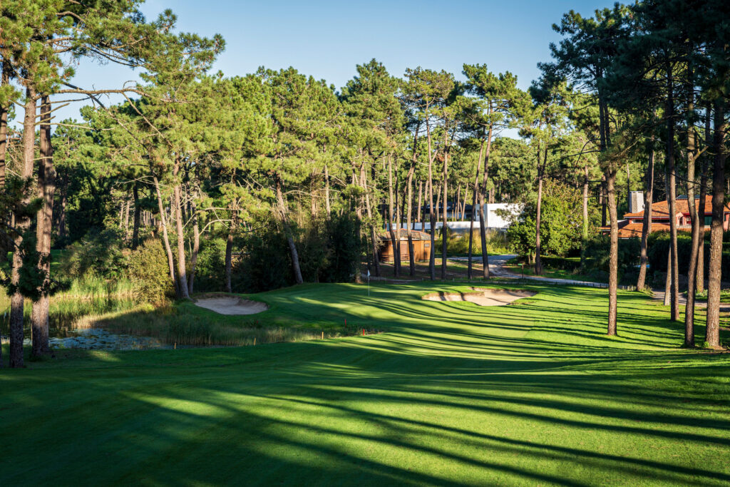 A hole with trees around and a bunker at Aroeira Challenge Golf Course