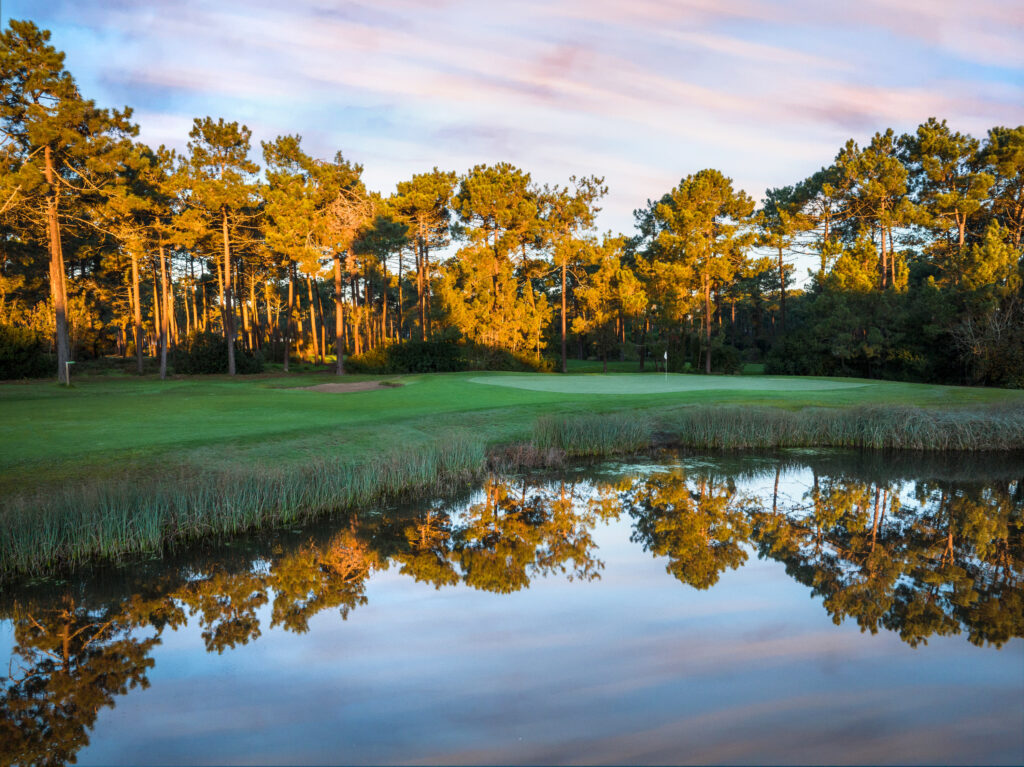 A hole with a lake and trees around at Aroeira Challenge Golf Course