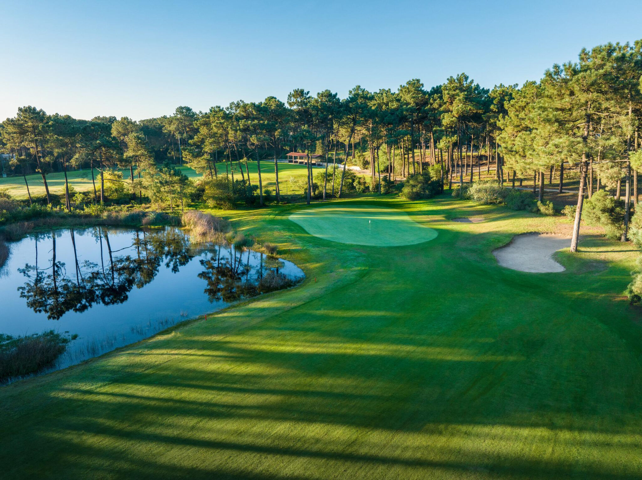 A hole with a lake and trees around at Aroeira Challenge Golf Course