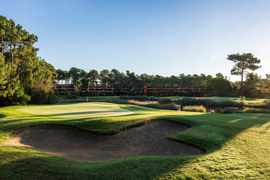 A hole with a bunker and trees in background at Aroeira Challenge Golf Course