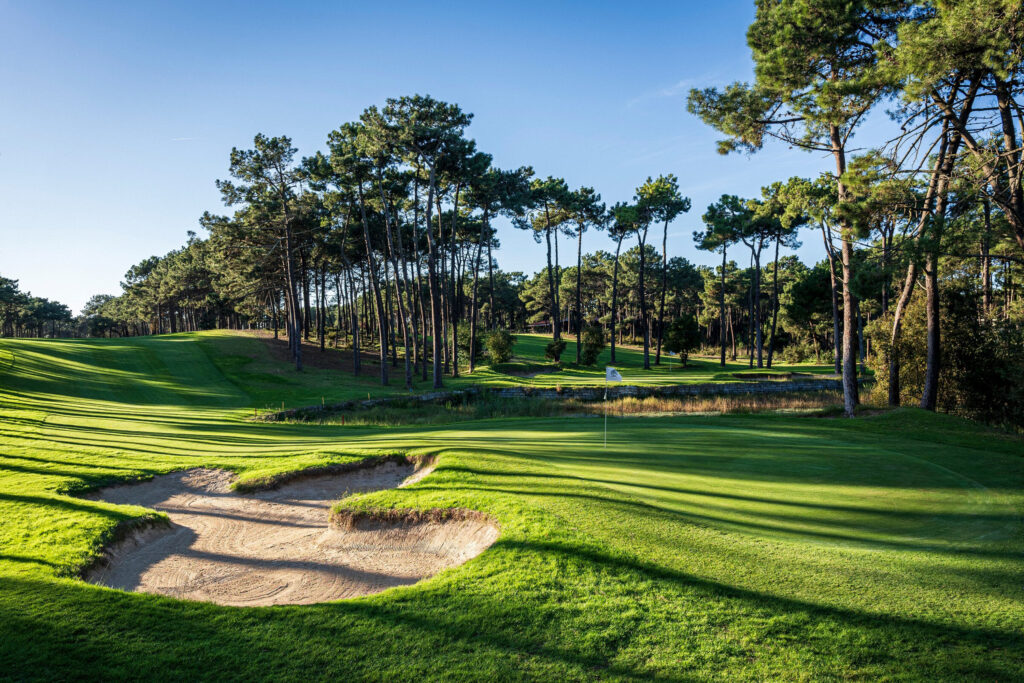 A hole with a bunker and trees around it at Aroeira Pines Classic Golf Course