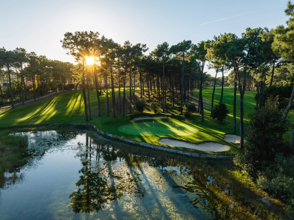 A hole with trees around and a lake at Aroeira Pines Classic Golf Course