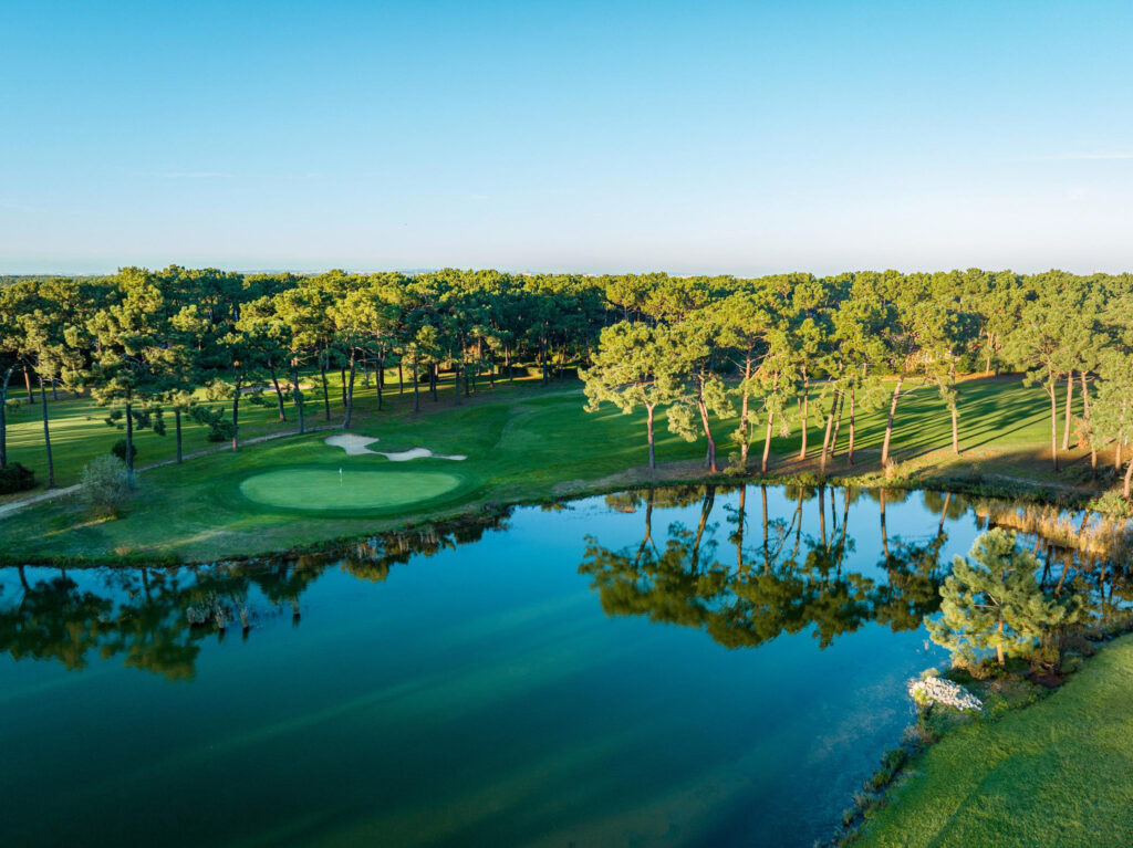 Aerial view of a hole at Aroeira Pines Classic Golf Course with trees and a lake