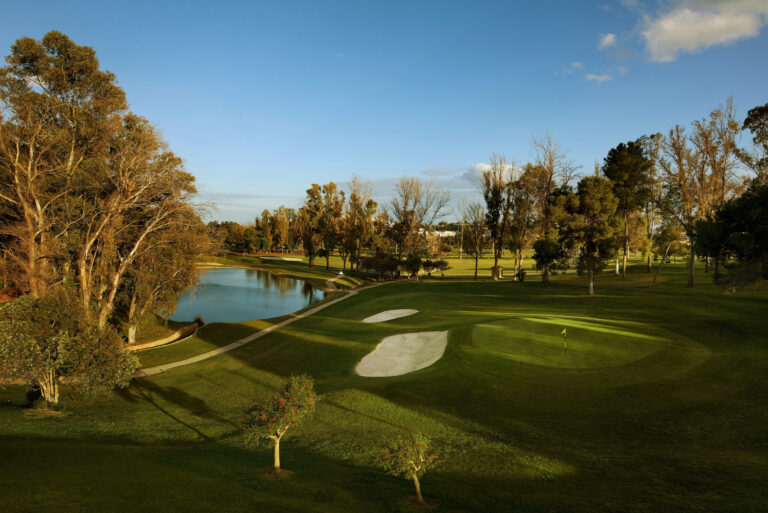 Hole with yellow flag at Atalaya - Old Golf Course with bunkers and lake