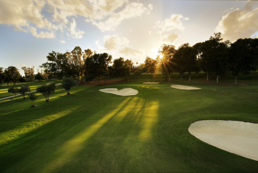 Hole with red flag and bunkers with trees around at Atalaya - Old Golf Course