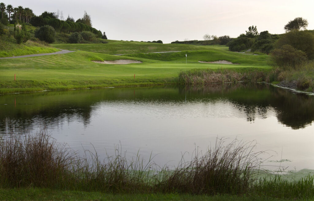 Lake with hole and bunkers in background at Belas Clube de Campo Golf Course