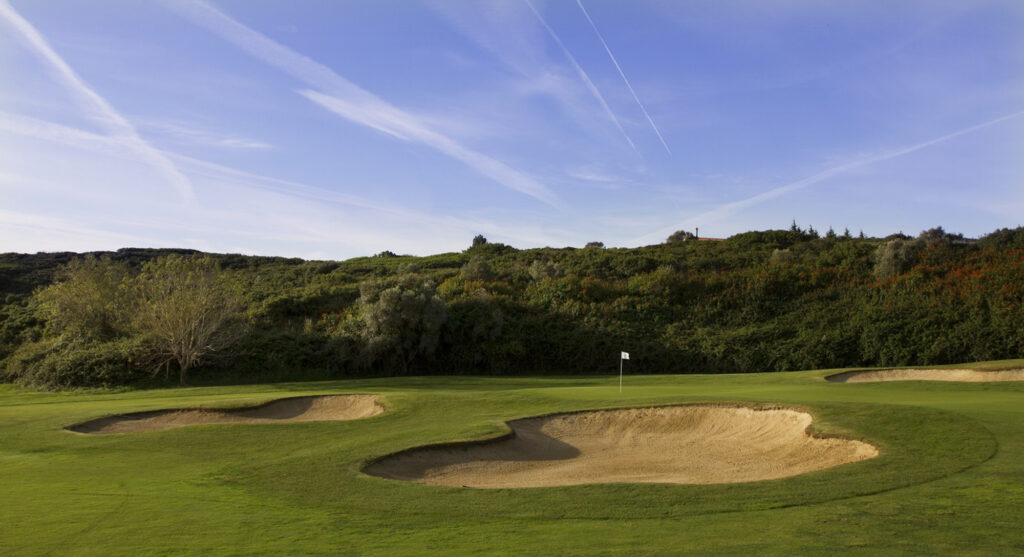 Bunkers by hole with trees in background at Belas Clube de Campo Golf Course