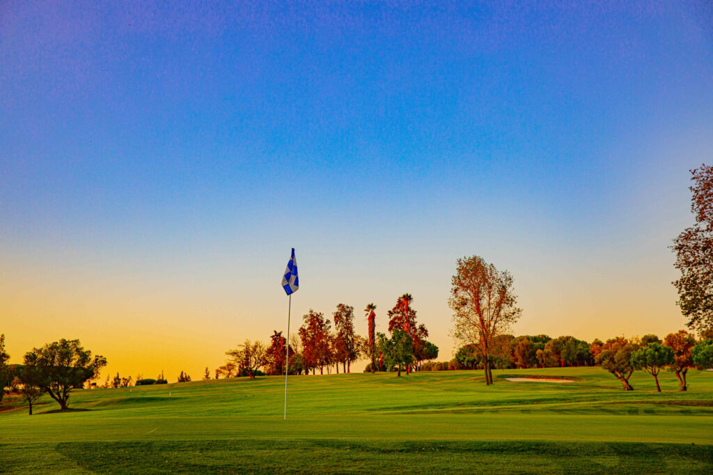 Hole with blue and white flag at sunset at Bellavista Golf Course