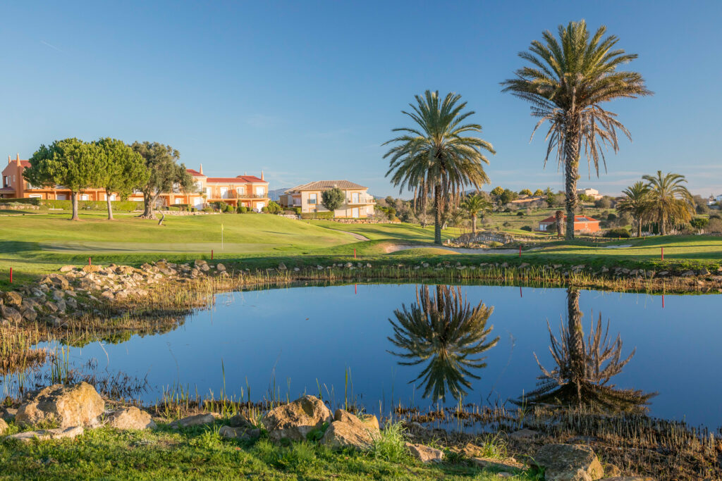 Lake with palm trees and buildings in background at Boavista Golf Course