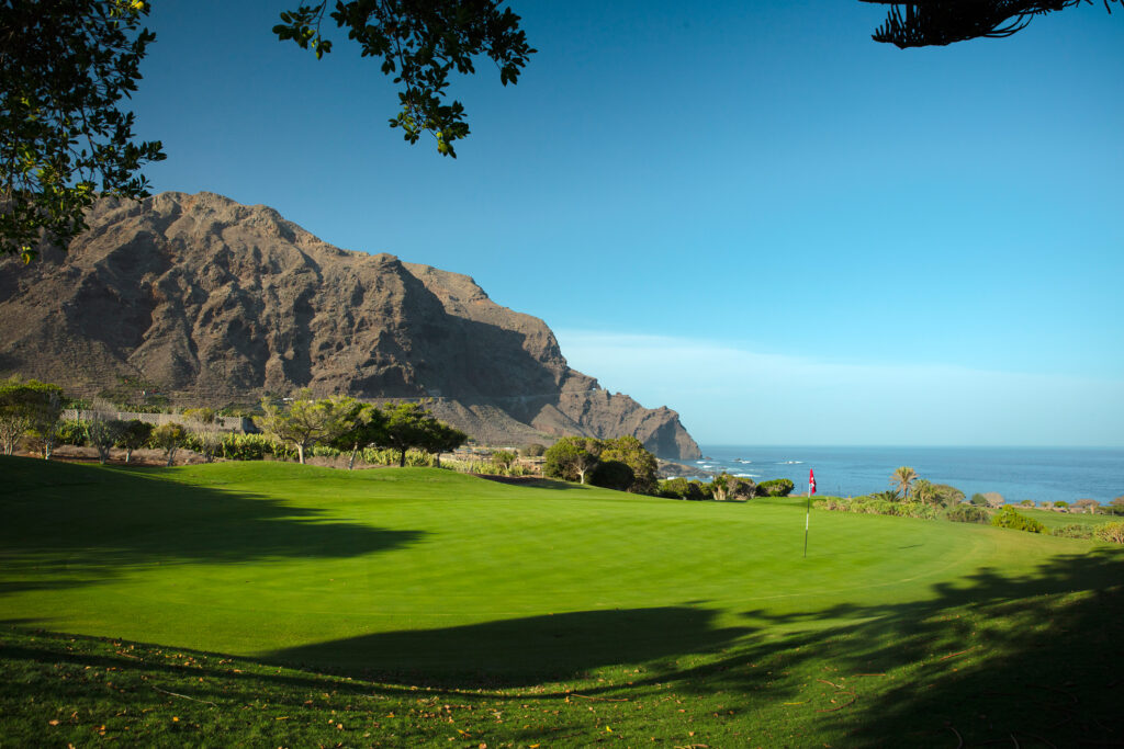 Hole with ocean view and mountains in distance at Buenavista Golf Course