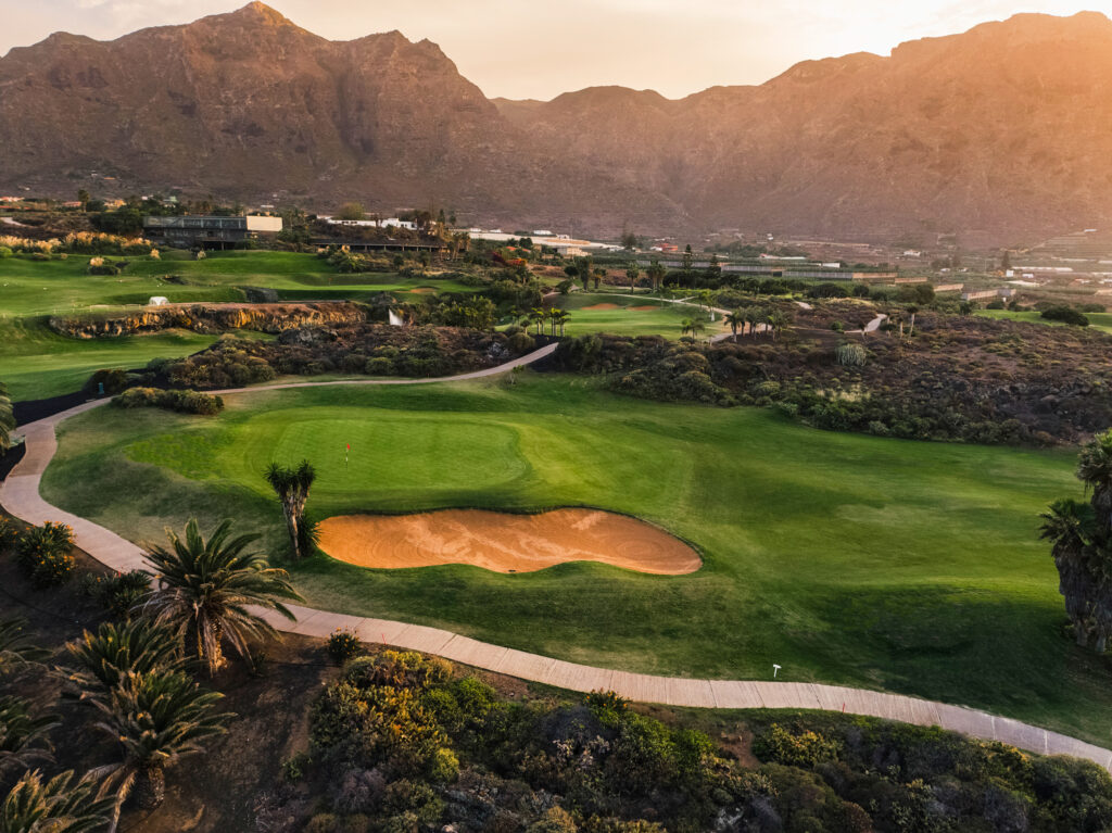 Hole with bunker and trees around at Buenavista Golf Course with mountains in distance