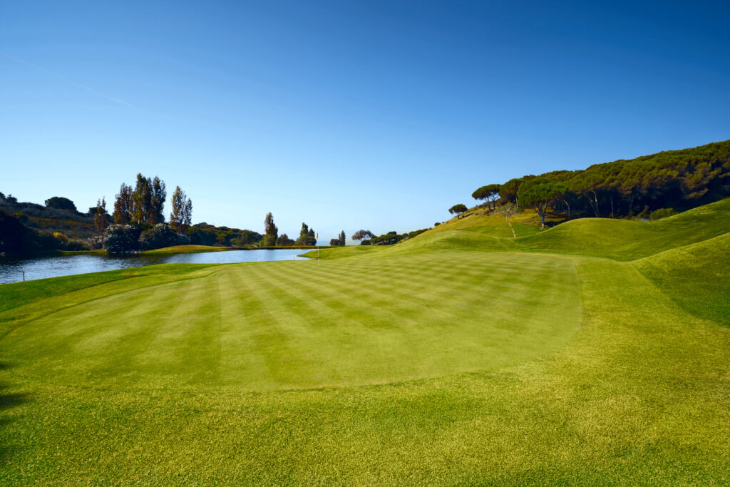 Hole with yellow flag and lake in background at Cabopino Golf Course