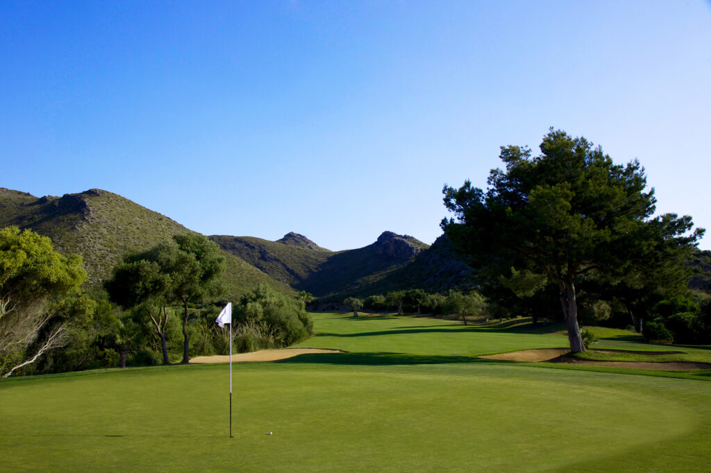 A hole at Capdepera Golf Course with hills and trees around