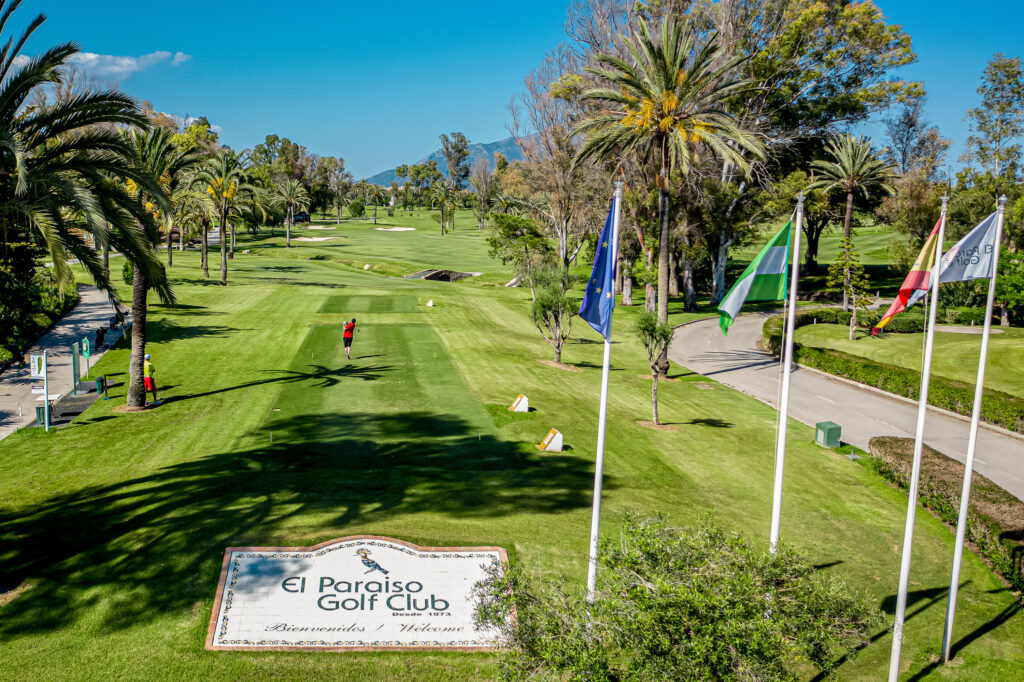 Tee box at El Paraiso Golf Course with national flags and trees around