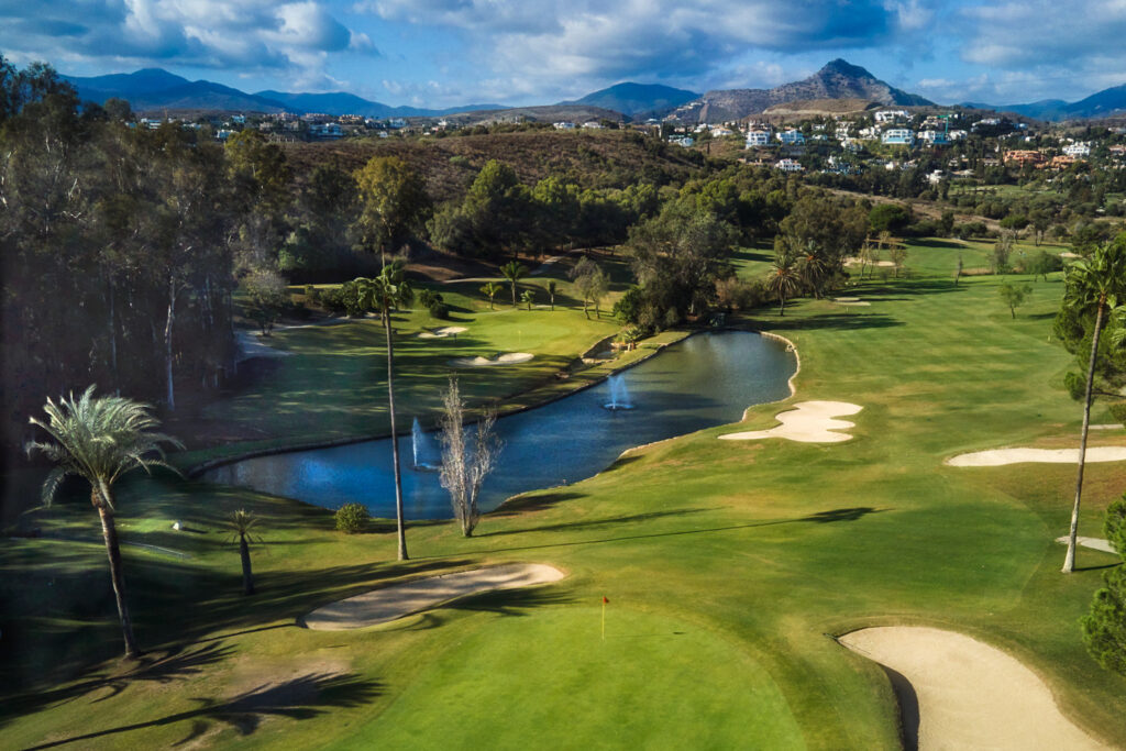 Fairway with bunkers and a lake at El Paraiso Golf Course with trees around