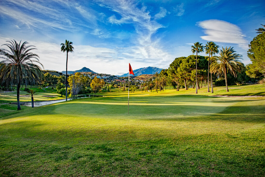 Hole with red flag at El Paraiso Golf Course with trees around