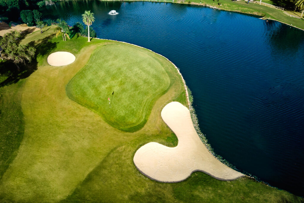 Aerial view of hole with bunkers at El Paraiso Golf Course with lake next to it