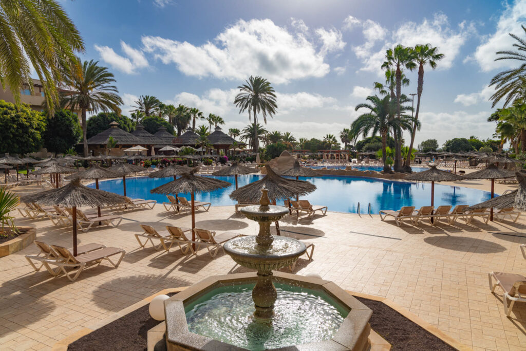 Elba Carlota Hotel with loungers around the pool and a fountain