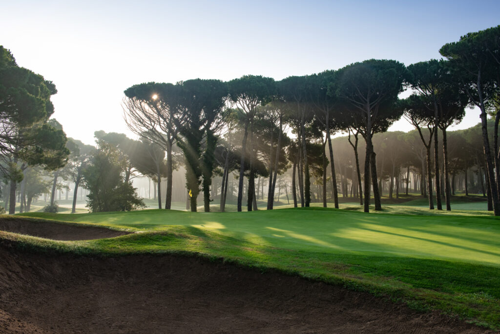 Hole with a yellow flag with bunkers and trees around at Emporda - Forest Course