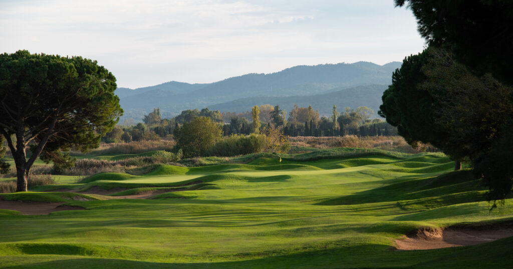 Fairway with bunkers and trees and hills in distance at Emporda - Forest Course