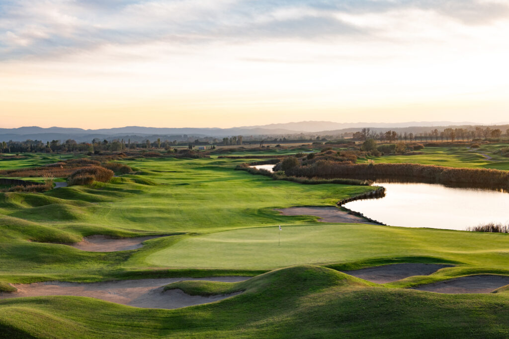 Fairway with lake and hole with white flag at Emporda - Links Course