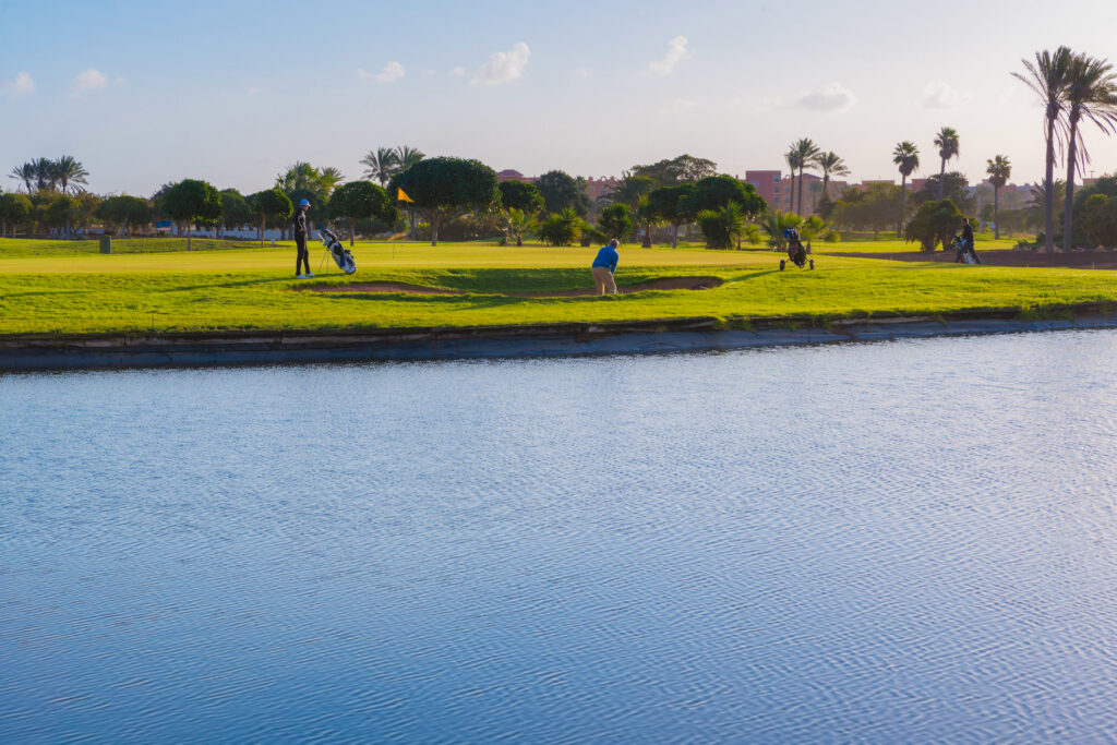 Lake with people playing golf in background at Fuerteventura Golf Club with trees around