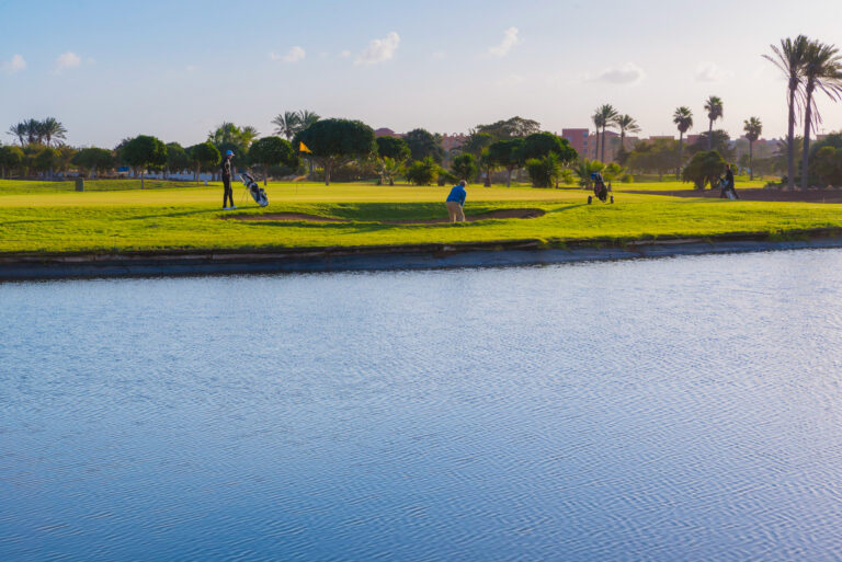 Lake with people playing golf in background at Fuerteventura Golf Club with trees around