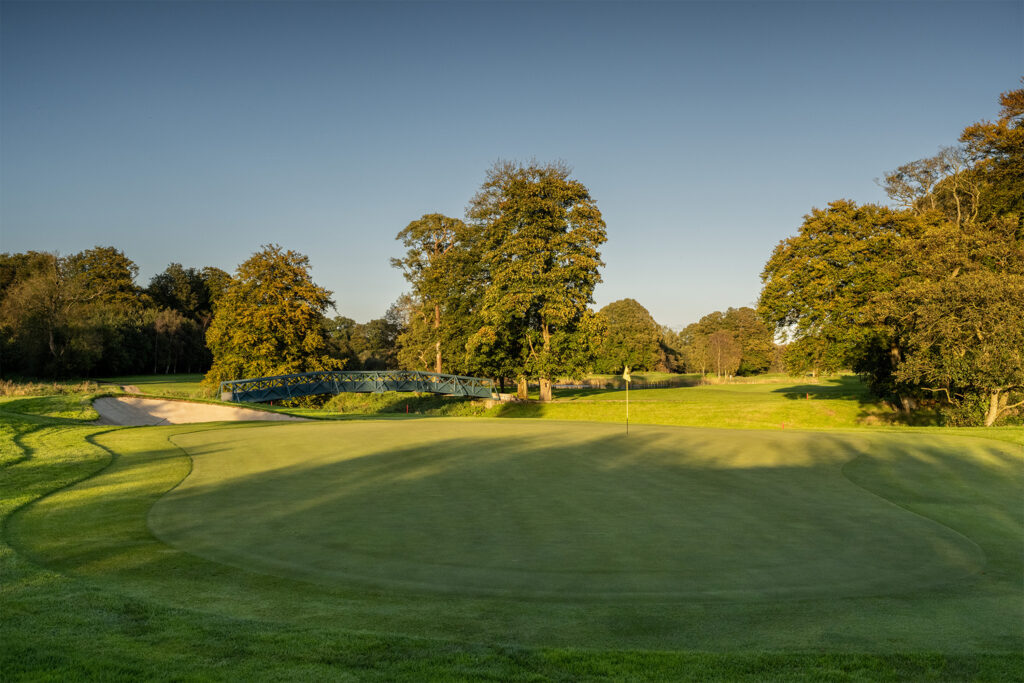 Hole with yellow flag at Galgorm Championship Course with trees around