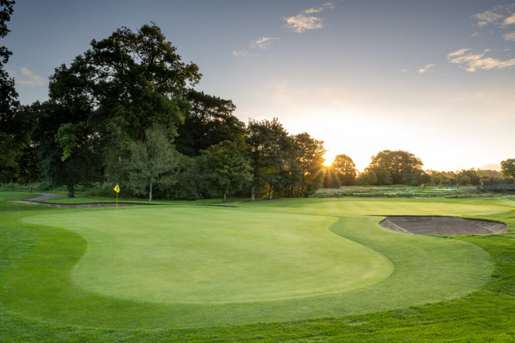 Hole with yellow flag with trees around at Galgorm Championship Course