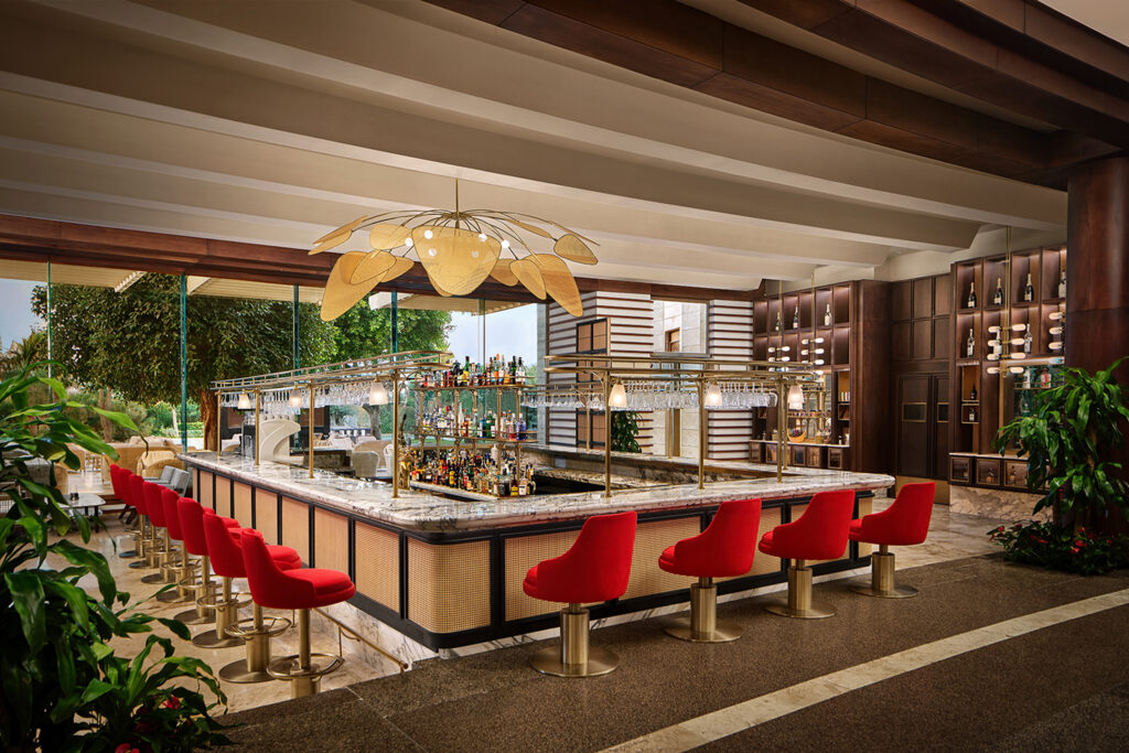 The lobby bar at the Gloria Serenity Golf Resort. This modern bar features plus red bar stools with a shiny marble bartop, wiith a plethora of drinks before the bar.