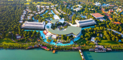 Overhead view of the Gloria Serenity Golf Resort, with the golf course in the background and lots of tall towering trees surrounding the outdoor space of the resort.