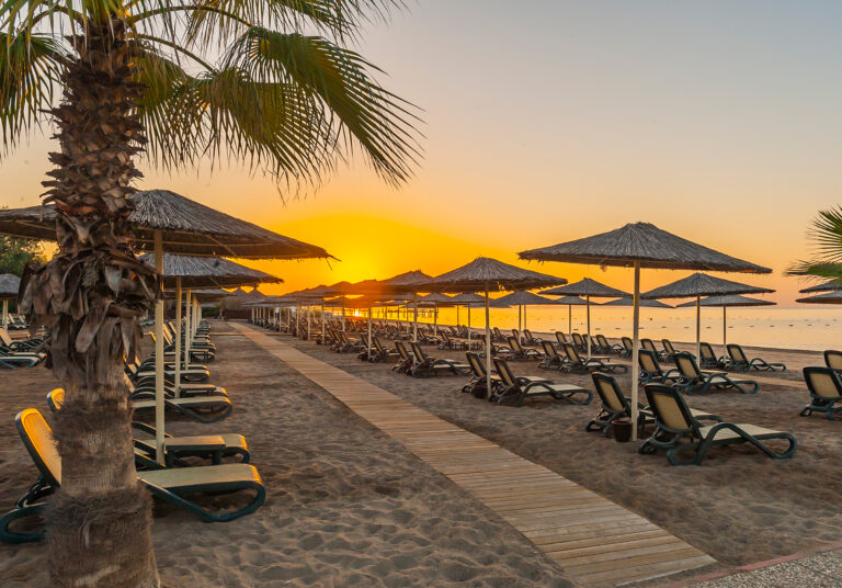 Sun loungers on beach at sunset at Gloria Verde Resort