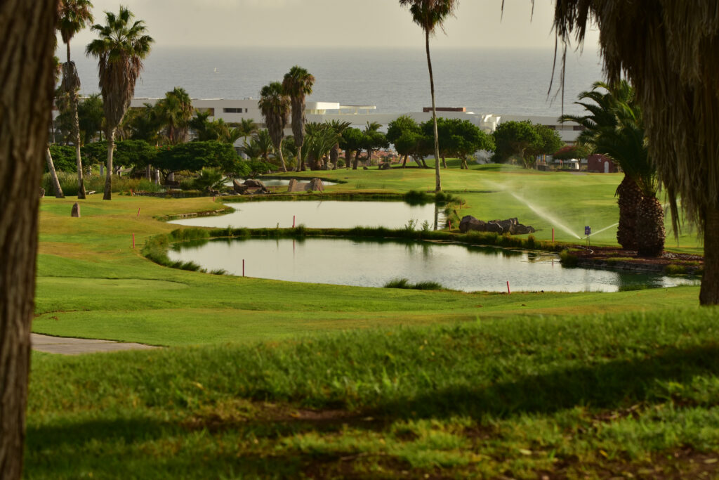 Lakes on fairway with trees around and building in distance at Golf Costa Adeje