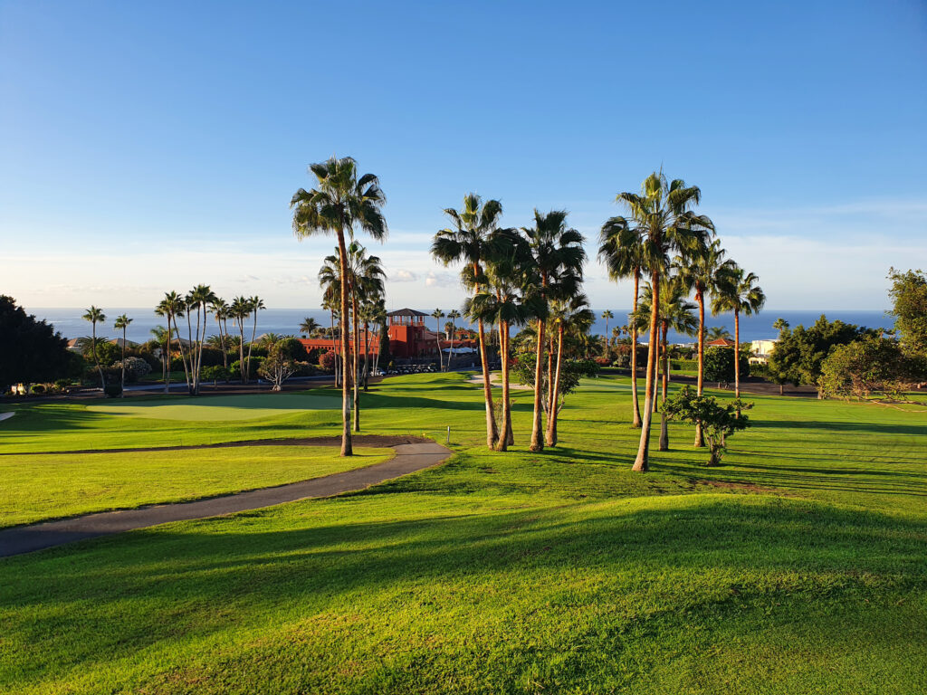 Fairway at Golf Costa Adeje with palm trees and building in the background