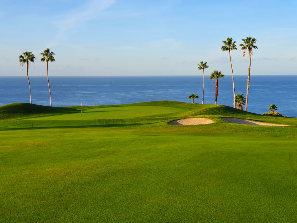 Hole with bunker and palm trees with ocean view at Golf Costa Adeje