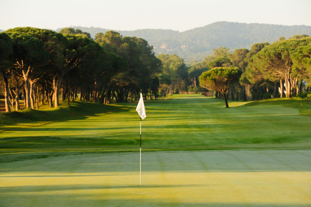 Hole with white flag and trees around at Golf de Pals Course