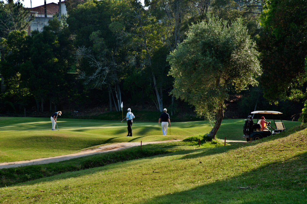 People playing golf at Golf do Estoril Golf Course with a buggy