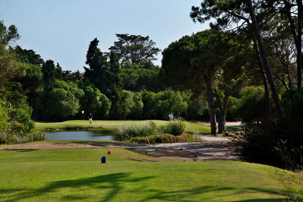 People playing golf at Golf do Estoril Golf Course surrounded by trees