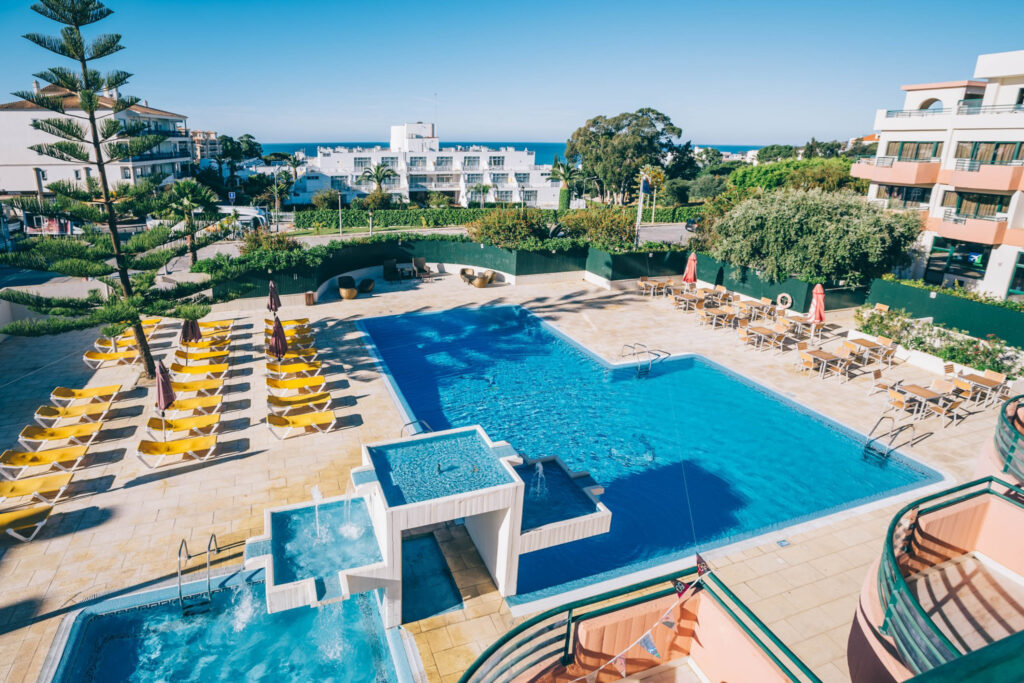 View of the outdoor pool with sun lounges at Grand Muthu Forte Da Oura