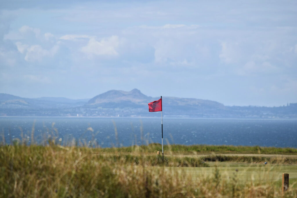 Hole with red flag at Gullane Golf Club - No. 2 Course with ocean in background