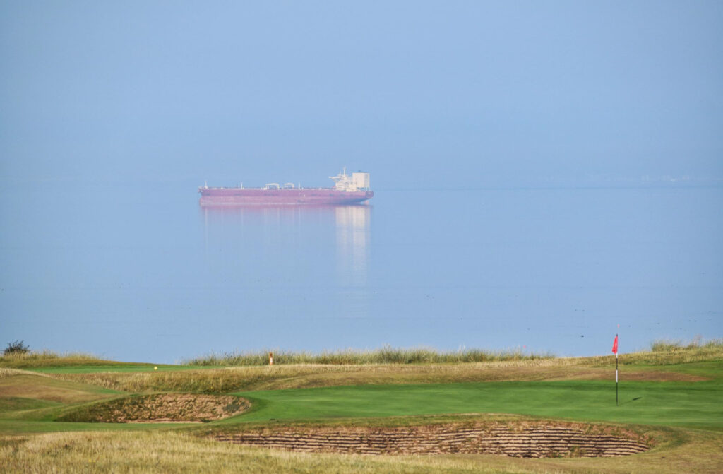 Hole with red flag at Gullane Golf Club - No. 2 Course with ship in background