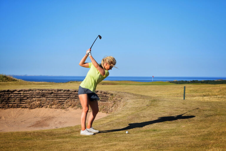 Person playing golf at Gullane Golf Club - No. 2 Course with ocean in distance