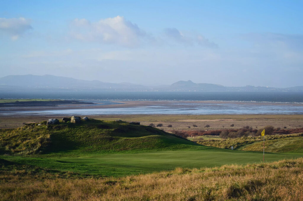 Hole with yellow flag at Gullane Golf Club – No. 3 Course with ocean in background